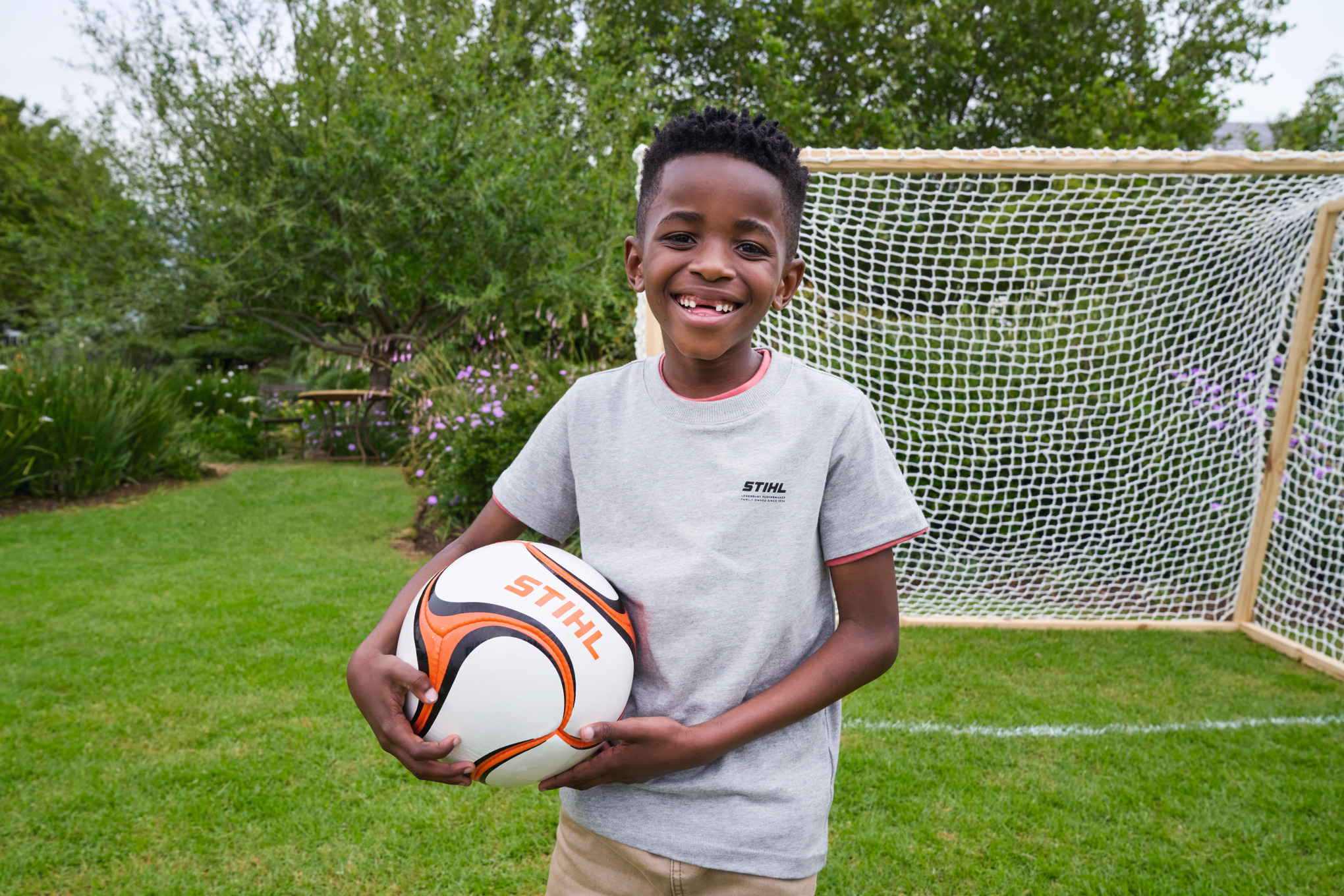 Um rapaz sorridente segura uma bola de futebol STIHL em frente à nova baliza